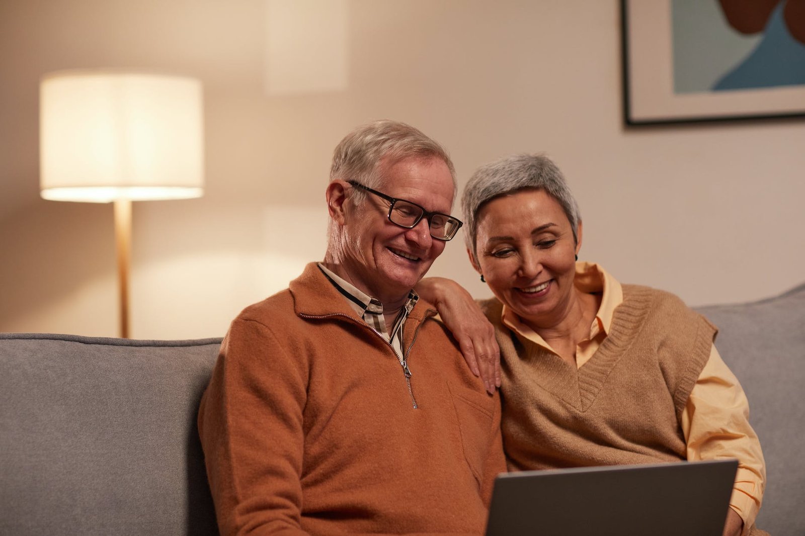 man and woman sitting on sofa while looking at a laptop reading funny wedding anniversary quotes