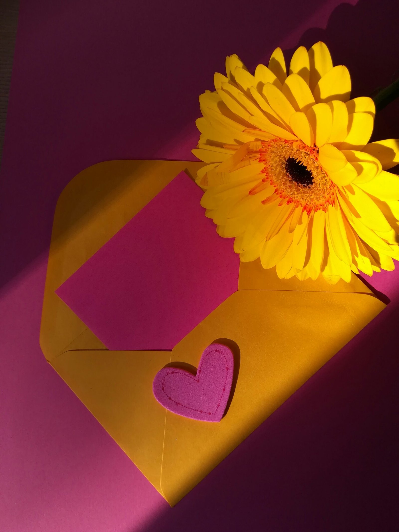 a yellow flower sitting on top of a yellow envelope